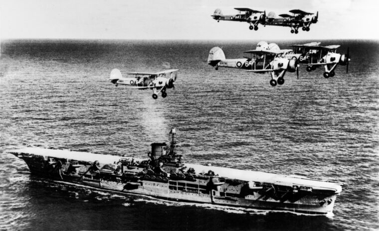 A formation of Fairey Swordfish torpedo bombers flies above the carrier HMS Ark Royal in 1939. An attack by Swordfish delivered the decisive blow against the German battleship Bismarck.