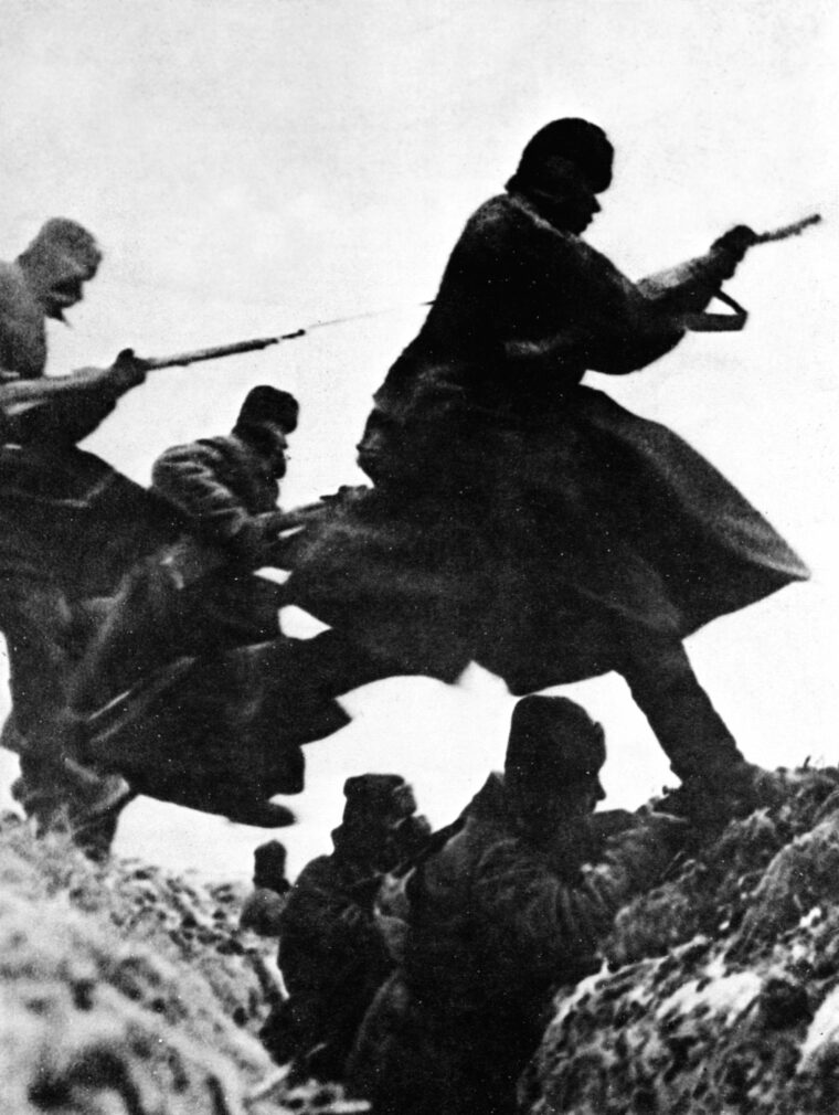 Uniformed against the cold, Soviet soldiers with fixed bayonets advance on the run toward entrenched German positions during bitter fighting in the winter of 1941-1942.