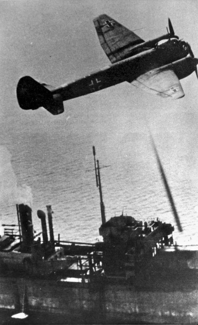 Flying just above the masts of the merchant ship Paulos Potter, a German twin-engine Junkers Ju-88 executes a daring bombing run against Convoy PQ-17. The vigor with which the German pilots pressed home their attacks was noted by British naval officers defending the convoy.