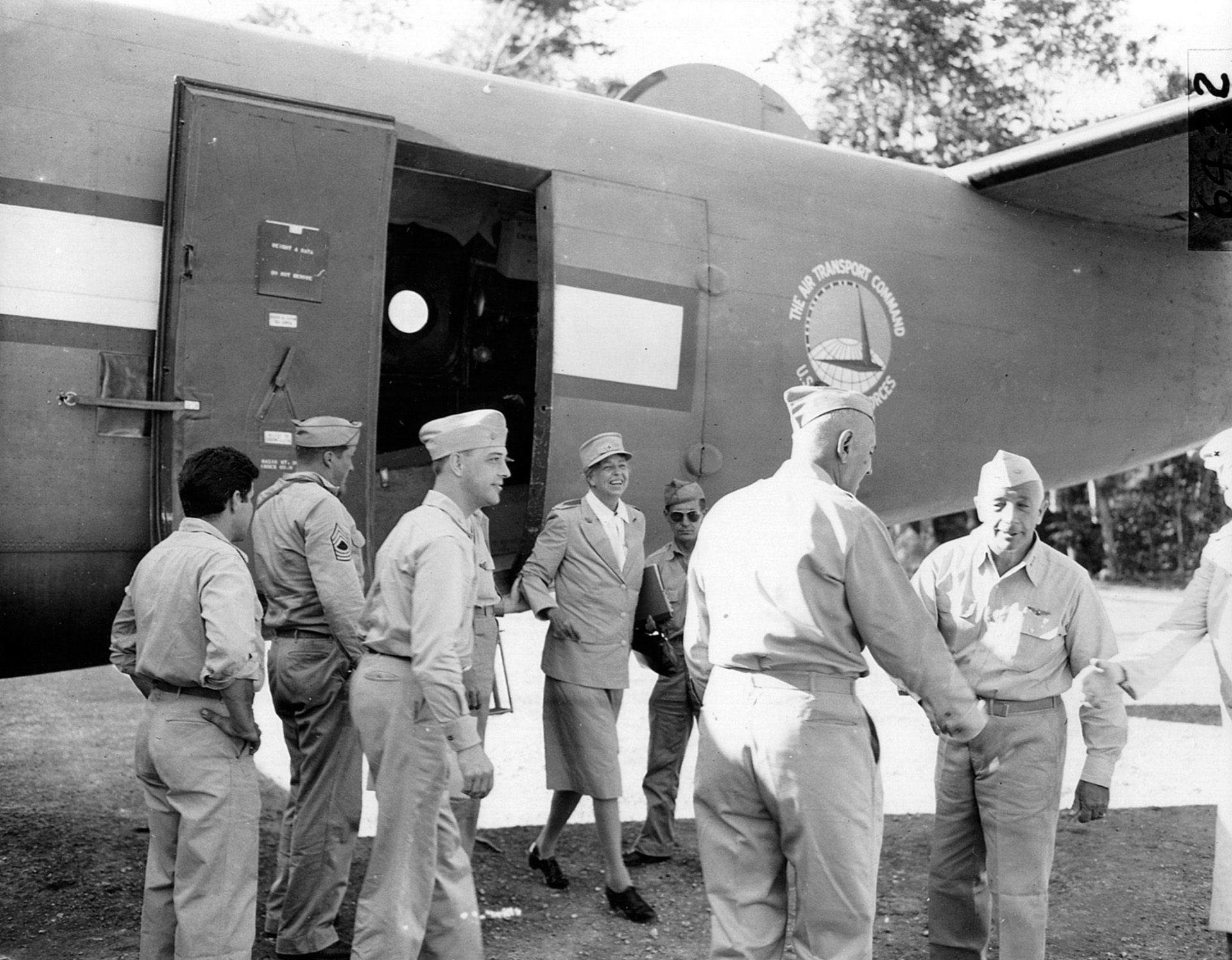 Major General Maxwell Murray (left) and Admiral Aubrey Fitch greet one another as they prepare to welcome First Lady Eleanor Roosevelt, exiting the aircraft, to Espiritu Santo in the New Hebrides, 1942.