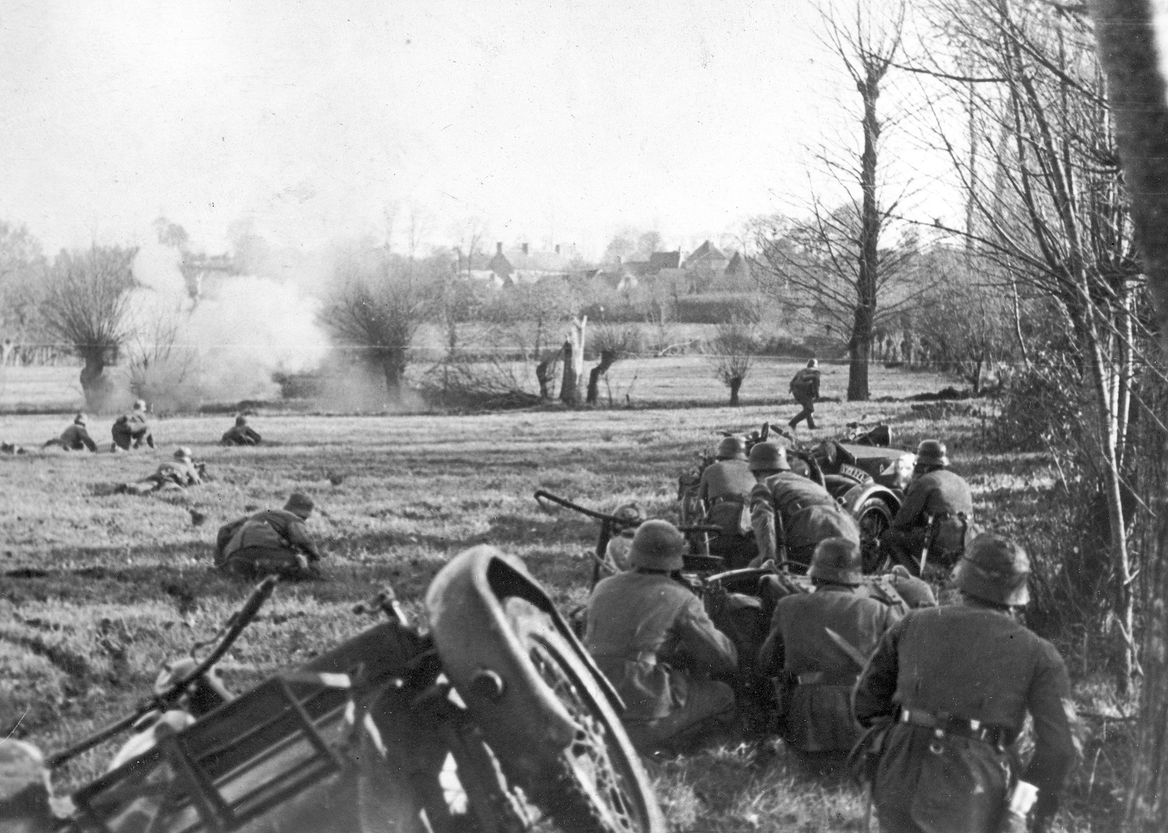 Temporarily halted by a machine-gun nest, members of a German motorcycle infantry platoon maneuver to silence the threat on the outskirts of a French village.