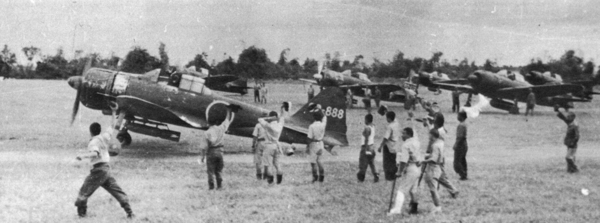 In this photo, a Japanese kamikaze pilot, his canopy open, taxis on Clark Field toward a rendezvous with death during an early suicide raid in October 1944. Ground crewmen shout encouragement to the doomed pilot. In the beginning, kamikaze raids were conducted by volunteers. Later, pilots were ordered to carry out the suicide missions.