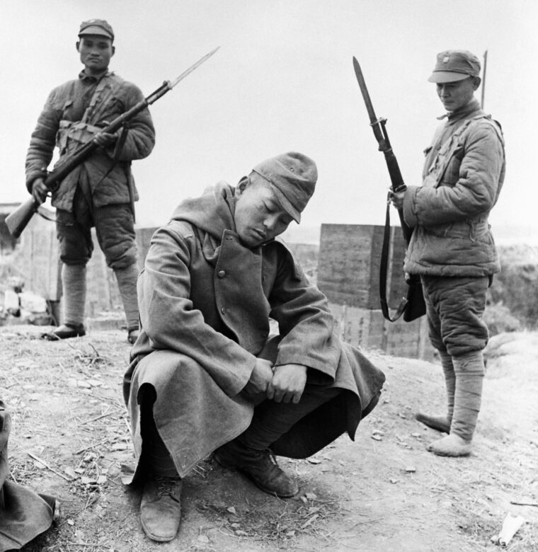 Crouching before his Chinese captors, a dejected Japanese soldier awaits his fate at Changde in Hunan Province. This soldier was captured as  the Chinese advanced on February 1, 1944. (© Bettmann/CORBIS)