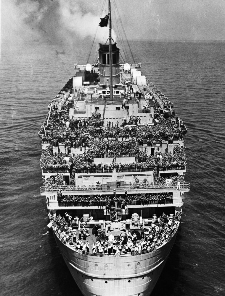 In this photo taken on June 20, 1945, from a hovering U.S. Coast Guard helicopter, the decks of the Queen Mary are packed with 14,000 American soldiers straining to gain a glimpse of the New York City skyline upon their return home from Europe. 