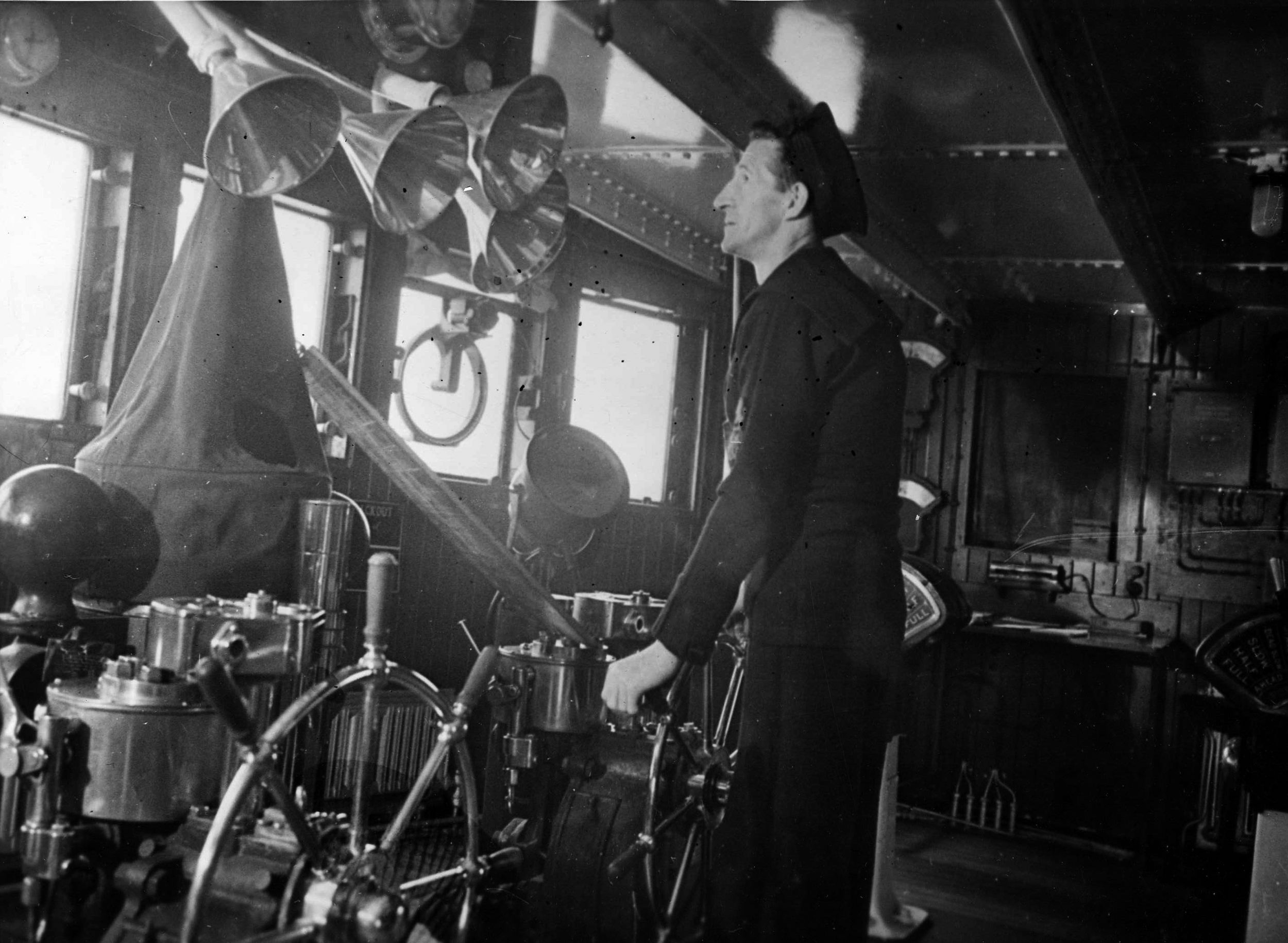 A veteran of the Queen Mary since her maiden voyage, Quartermaster William Hilton stands at one of the ship’s two wheels inside the large wheelhouse.
