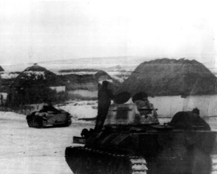 Moving toward the fighting at Kharkov during an offensive operation near the Don River, Red Army tanks advance through a temporarily quiet Russian village.