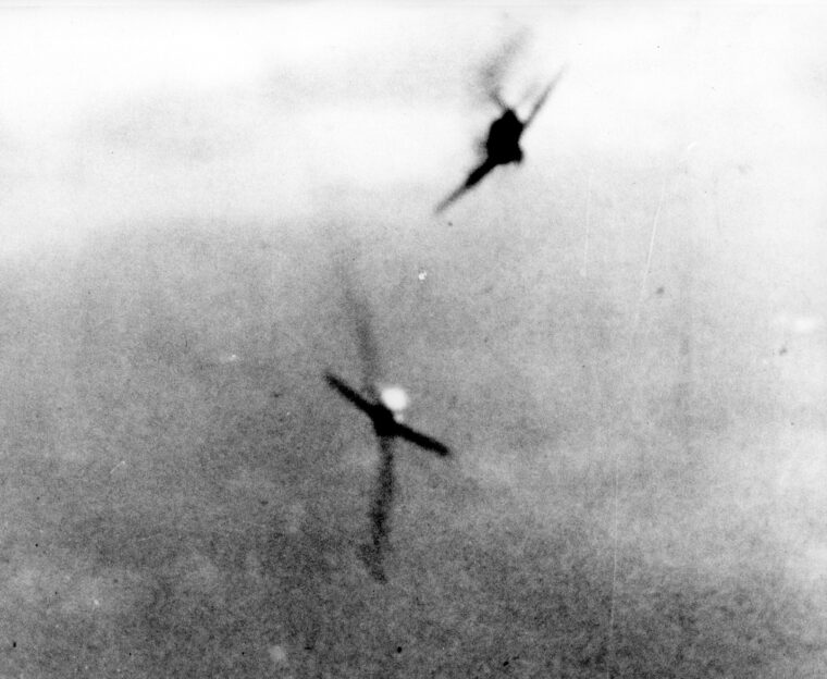 Locked in deadly combat, the guns of a Navy Hellcat rake a Japanese Zero during an aerial encounter above the Marianas.