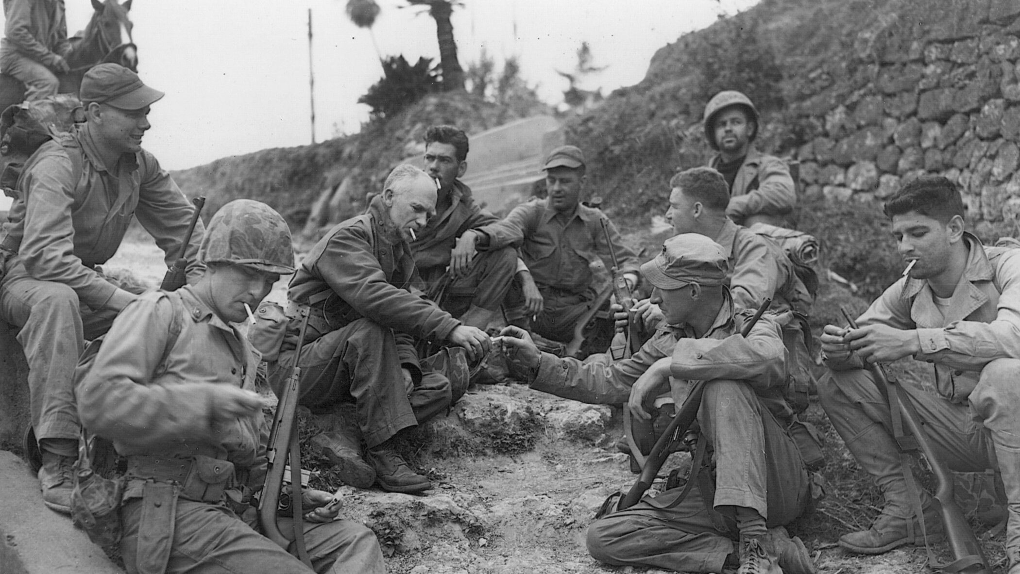 On April 18, 1945, only days before his death, famed war correspondent Ernie Pyle shares cigarettes with a group of Marines from the U.S. 1st Division on the wartorn island of Okinawa.