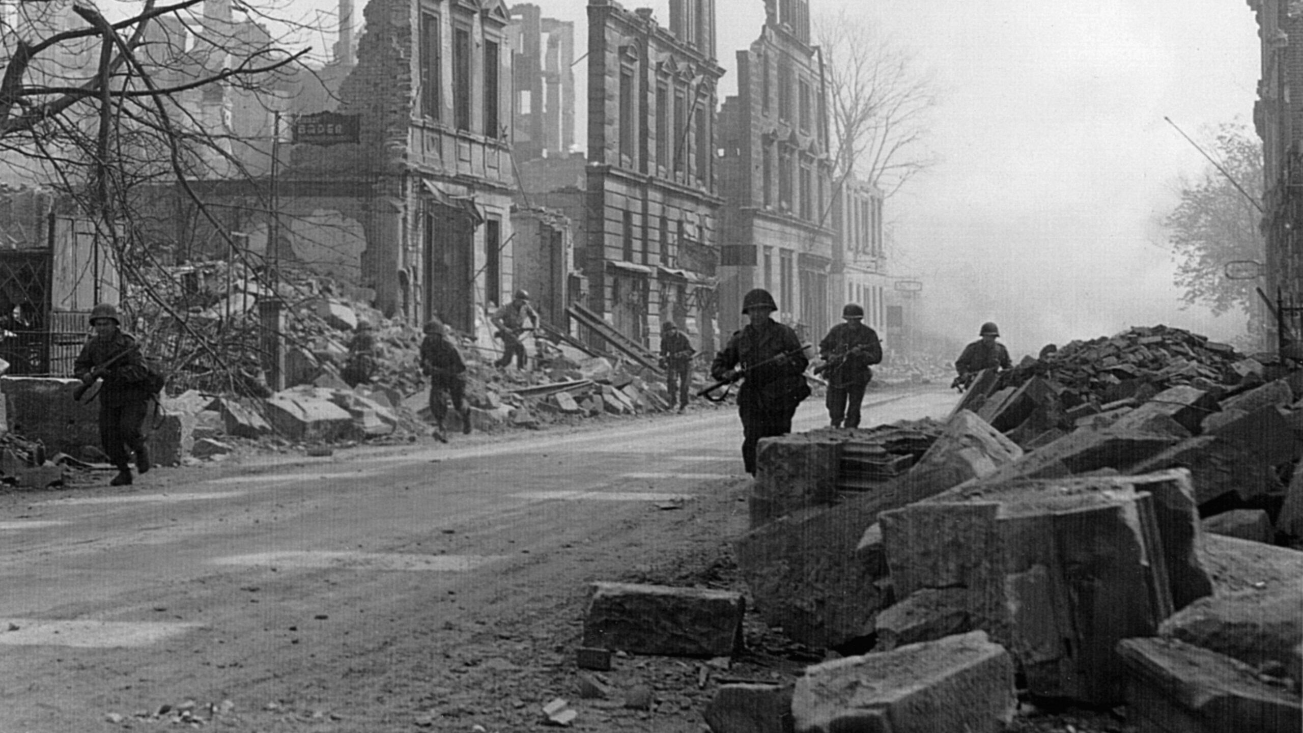 Soldiers of the 399th Infantry Regiment move quickly past the bombed-out shells of buildings in the German city of Heilbronn during the last days of major combat in the European Theater.