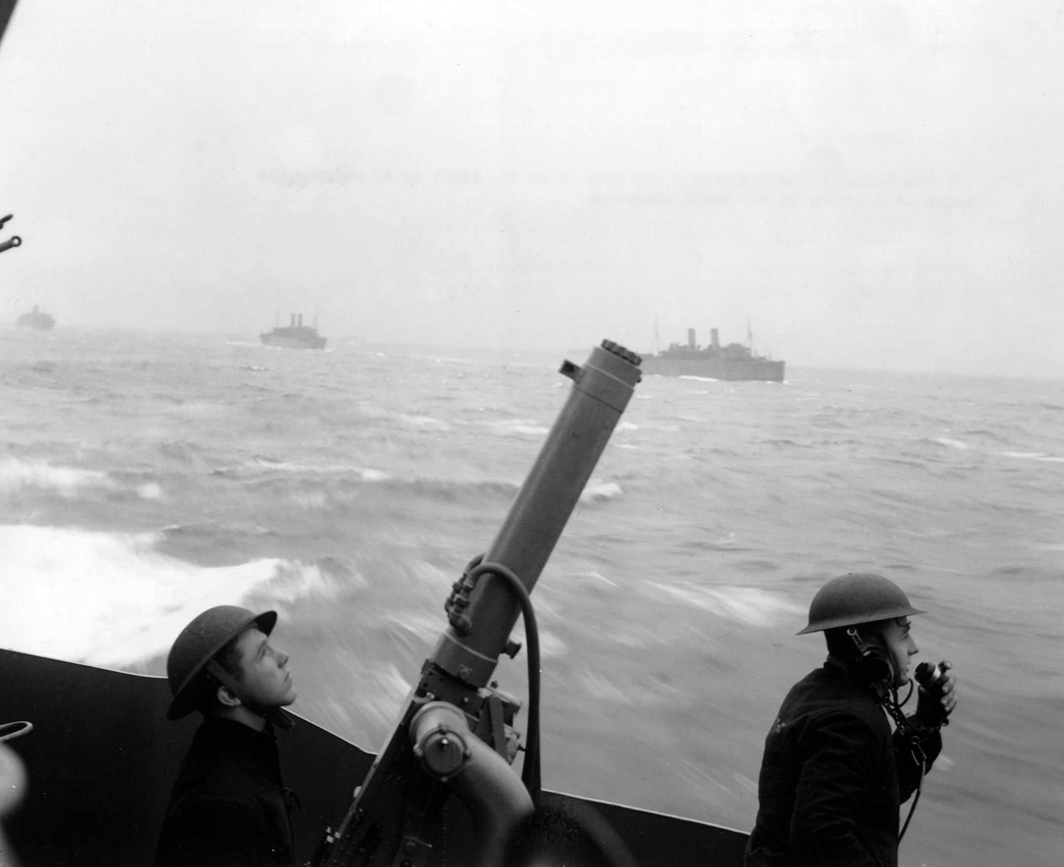 Scanning the skies above the North Atlantic, the crew of a shipboard machine gun stands at the ready. Often, a lone reconnaissance plane appeared initially, but was quickly followed by dive-bombers and torpedo planes.