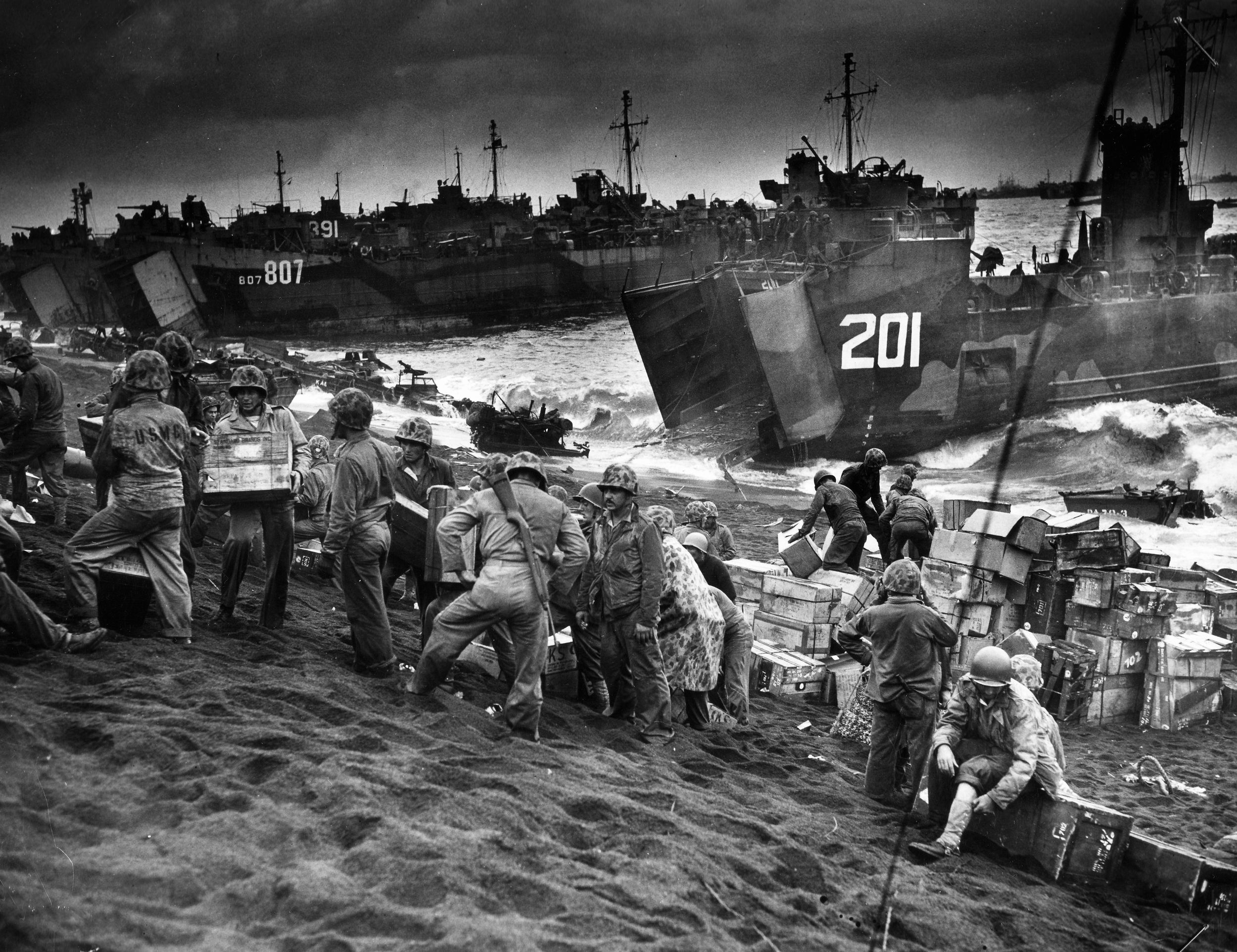 Within hours of the Marine landings on Iwo Jima, the U.S. Navy and Coast Guard crewmen of landing craft and LSTs set about the business of unloading supplies and equipment on the black beaches of the island. The loose sand proved difficult for vehicles to negotiate.