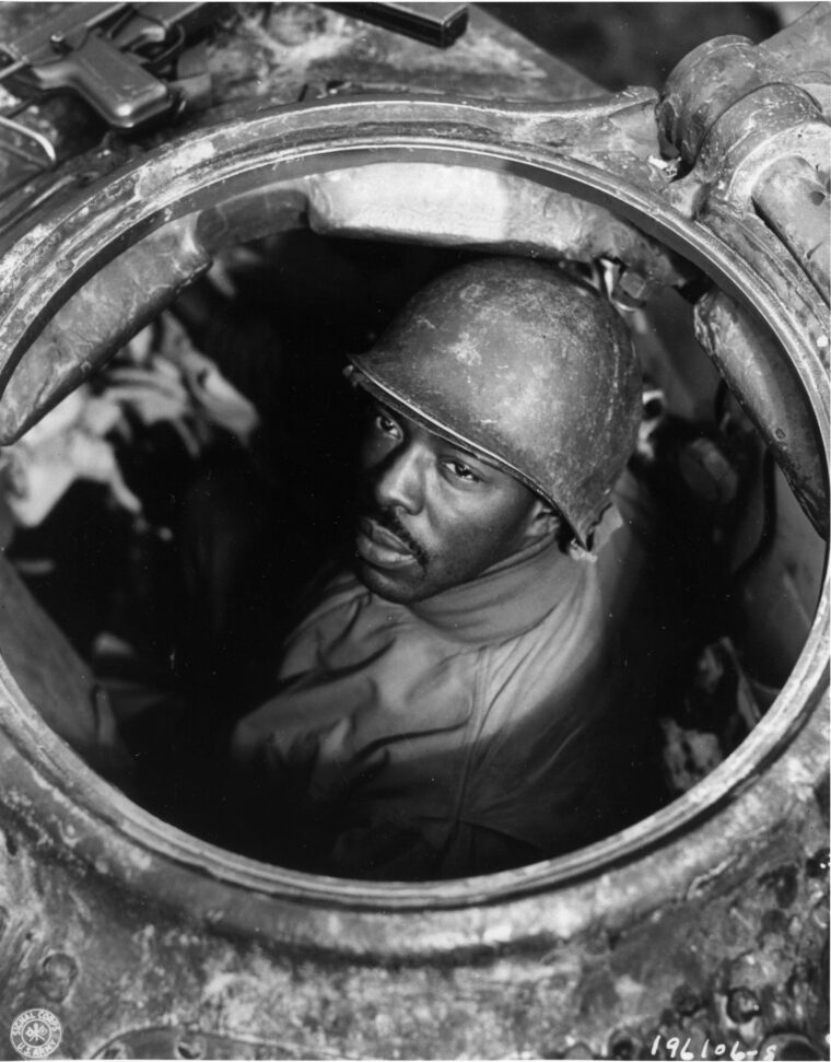 Peering through the open hatch of an M4 Sherman tank, Corporal Carlton Chapman served as a machine gunner with a motor transport company near Nancy, France.