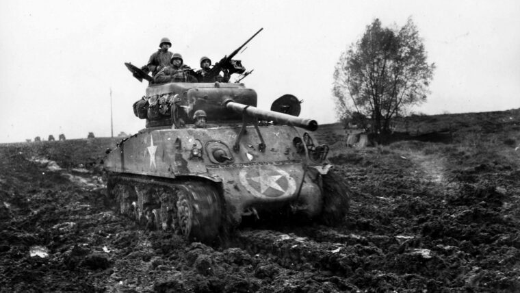 Rolling across a muddy field in France, the Sherman tank of Sergeant Harvey Woodward and his crew heads for the front. Shortly after this photograph was taken, the tank was hit by enemy fire and the entire crew killed.