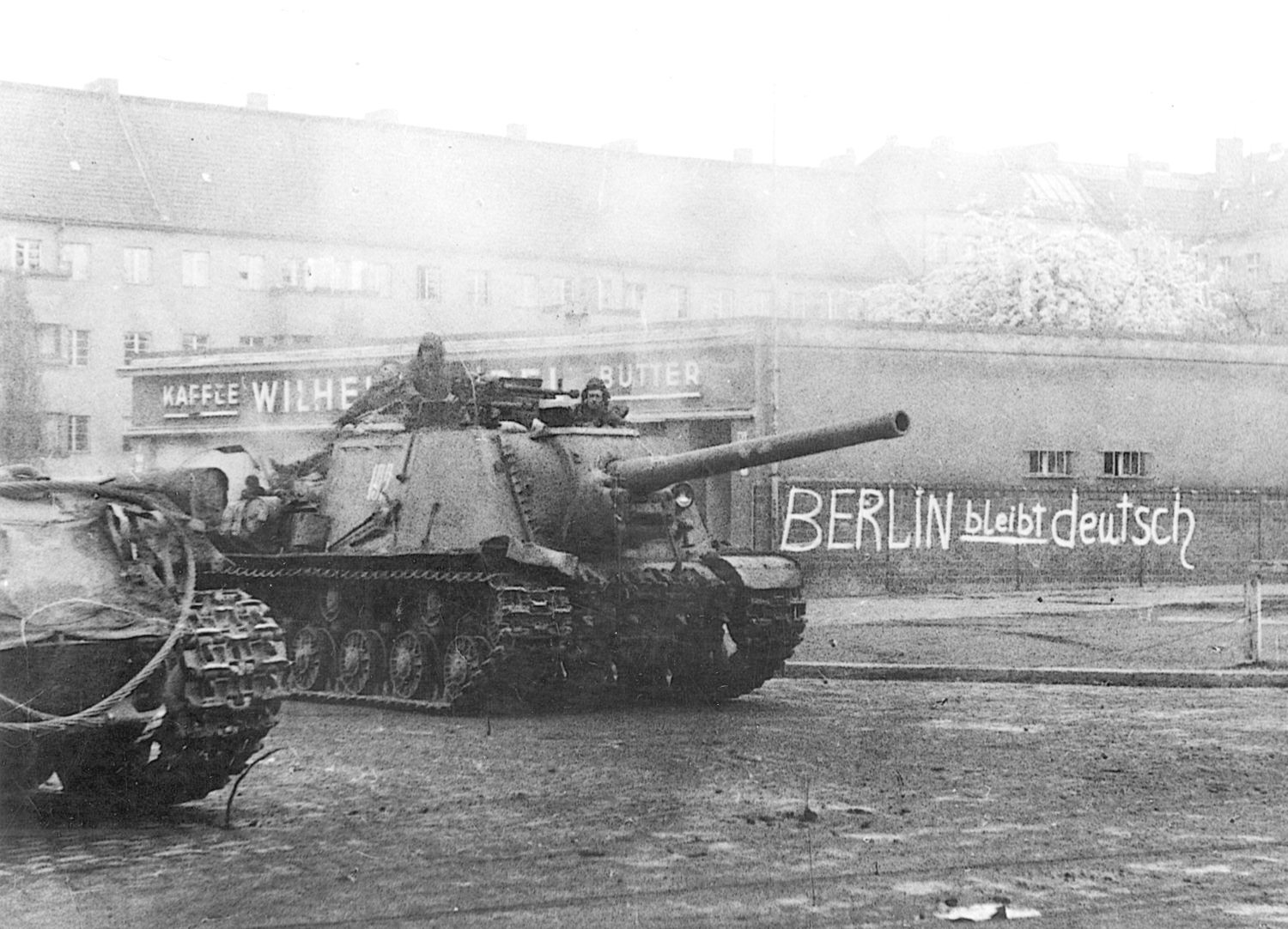 Soviet tanks advance through Berlin. The graffiti on the wall reads “Berlin Forever German.”