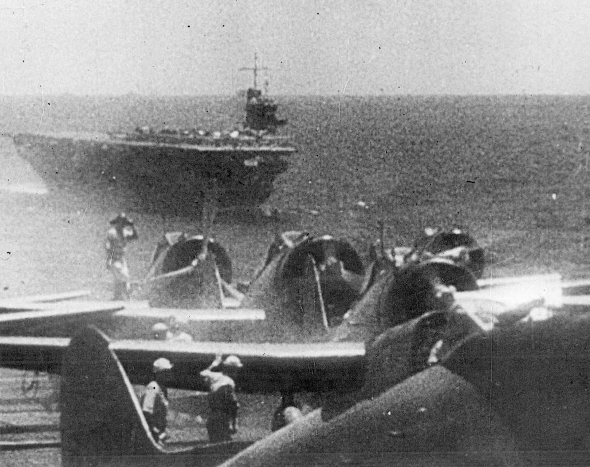 Crewmen tend to aircraft aboard a Japanese carrier, while a sister flattop plows ahead nearby.