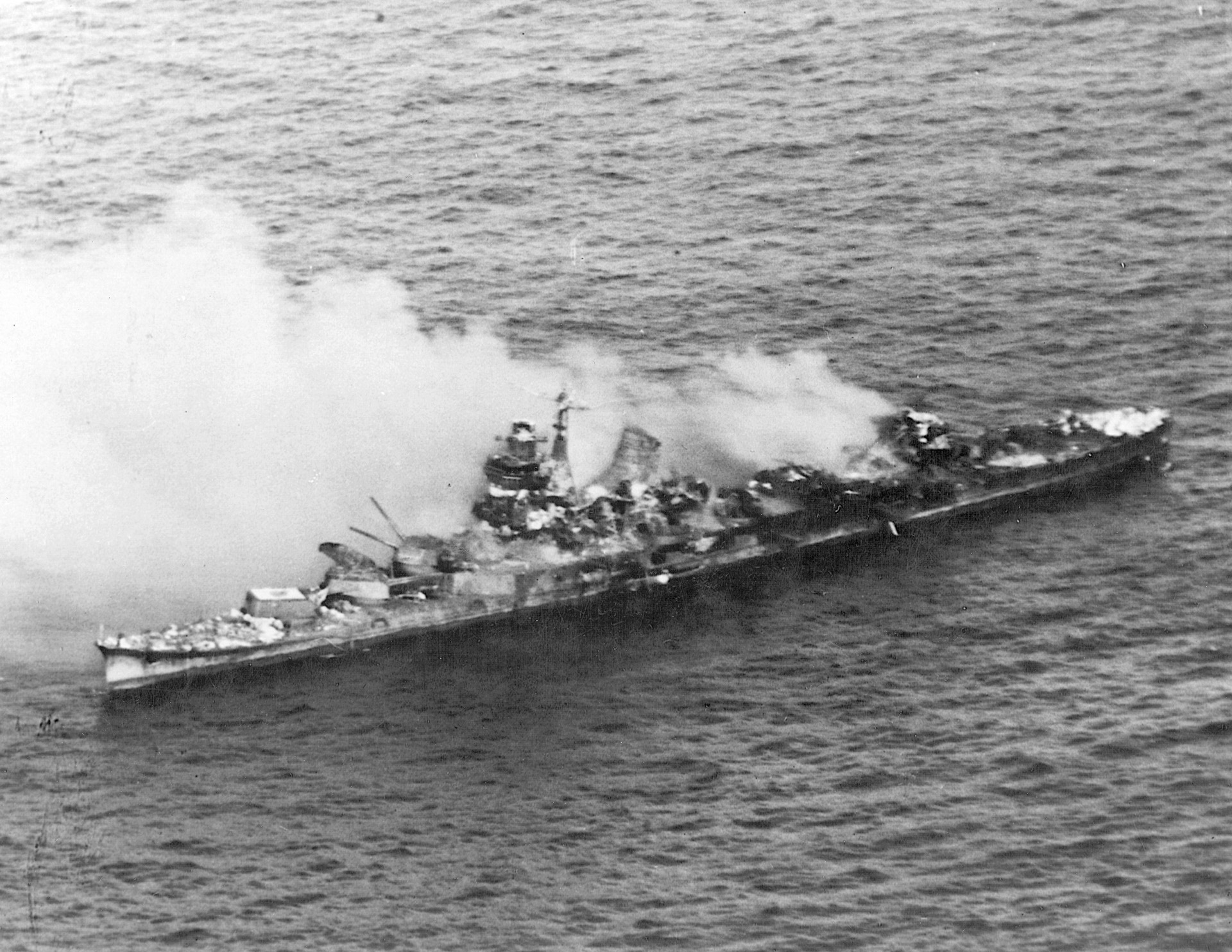 The Japanese heavy cruiser Mikuma wallows with her decks nearly awash after attacks by American aircraft.