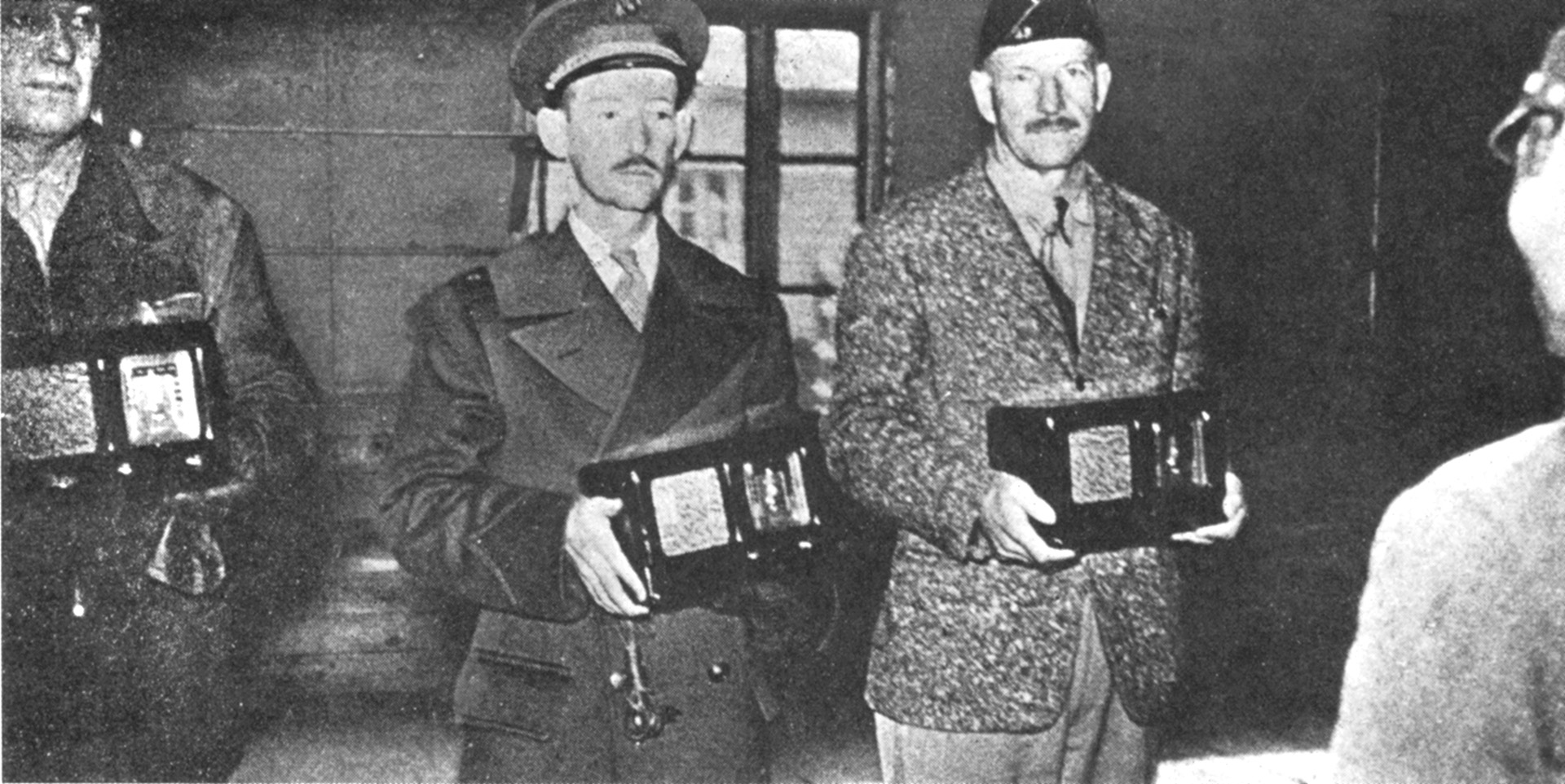 In captivity at Shanghai, Marine Major James P. Devereux (center), commander of the American garrison on Wake, poses with other prisoners. The radios were presented as a propaganda ploy and rigged to receive only Japanese broadcasts.