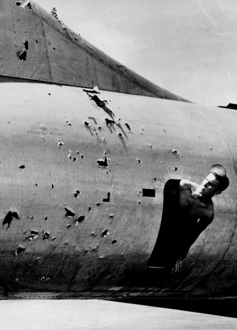 Peering from inside his B-29, a relieved crewman surveys the damage done to the heavy bomber by Japanese antiaircraft fire. The capture of Iwo Jima provided a haven for damaged bombers returning from Japan and saved thousands of lives. 