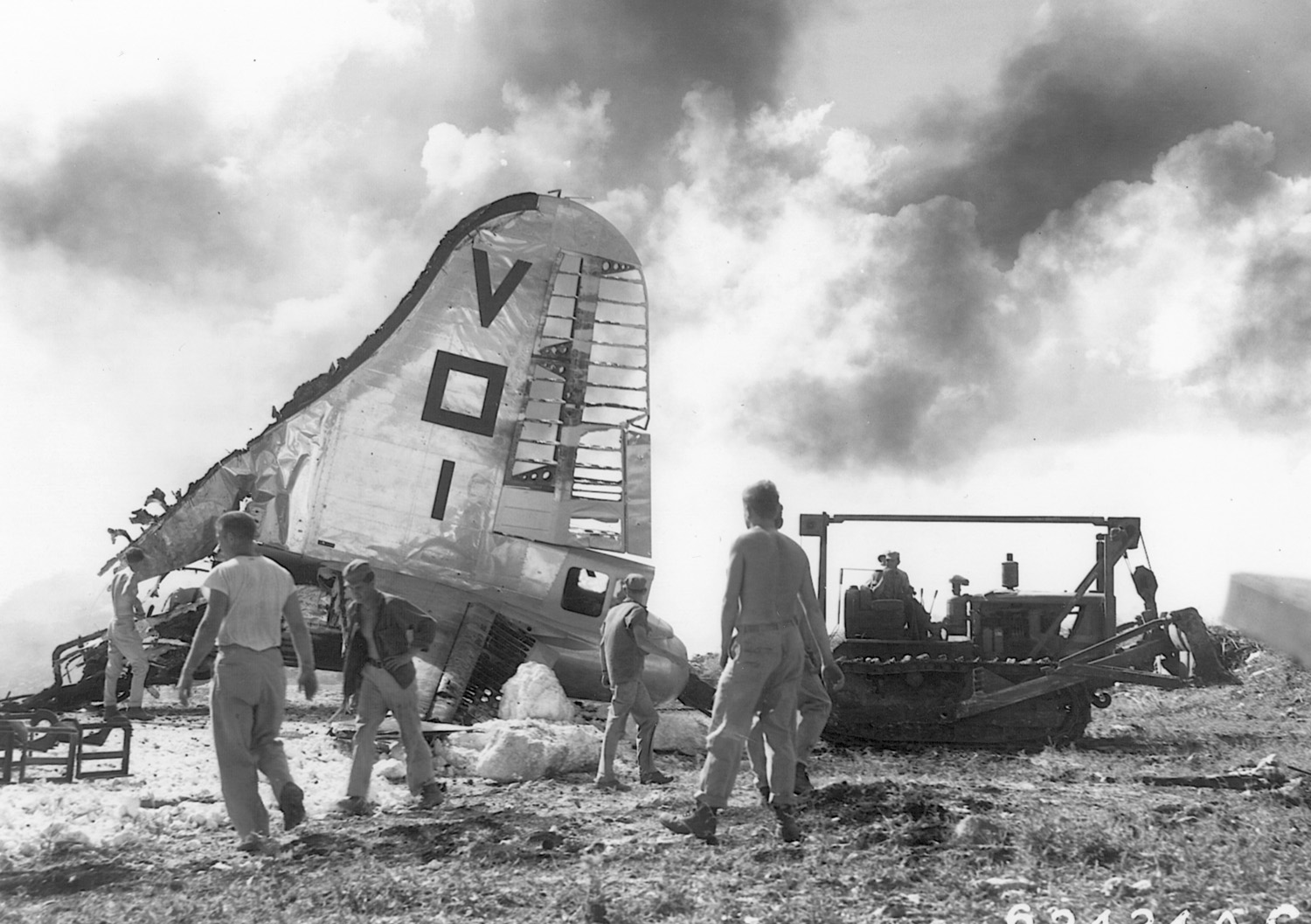 Following a Japanese raid on the U.S. airbase at Saipan, November 27, 1944, the tail section of a destroyed B-29 is visible as the rest of the bomber burns.