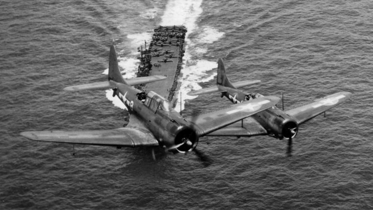 A pair of Douglas SBD Dauntless dive-bombers depart a carrier in the Pacific as they embark on a mission in late July 1944.