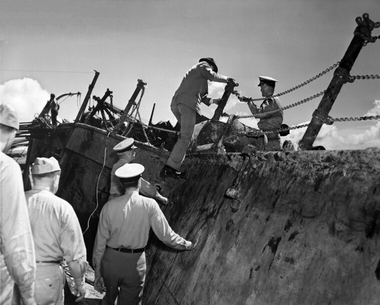 Assistant Secretary of the Navy Ralph Bard boards the wreck of USS Oklahoma (BB-37), at Pearl Harbor during salvage operations in April 1942.