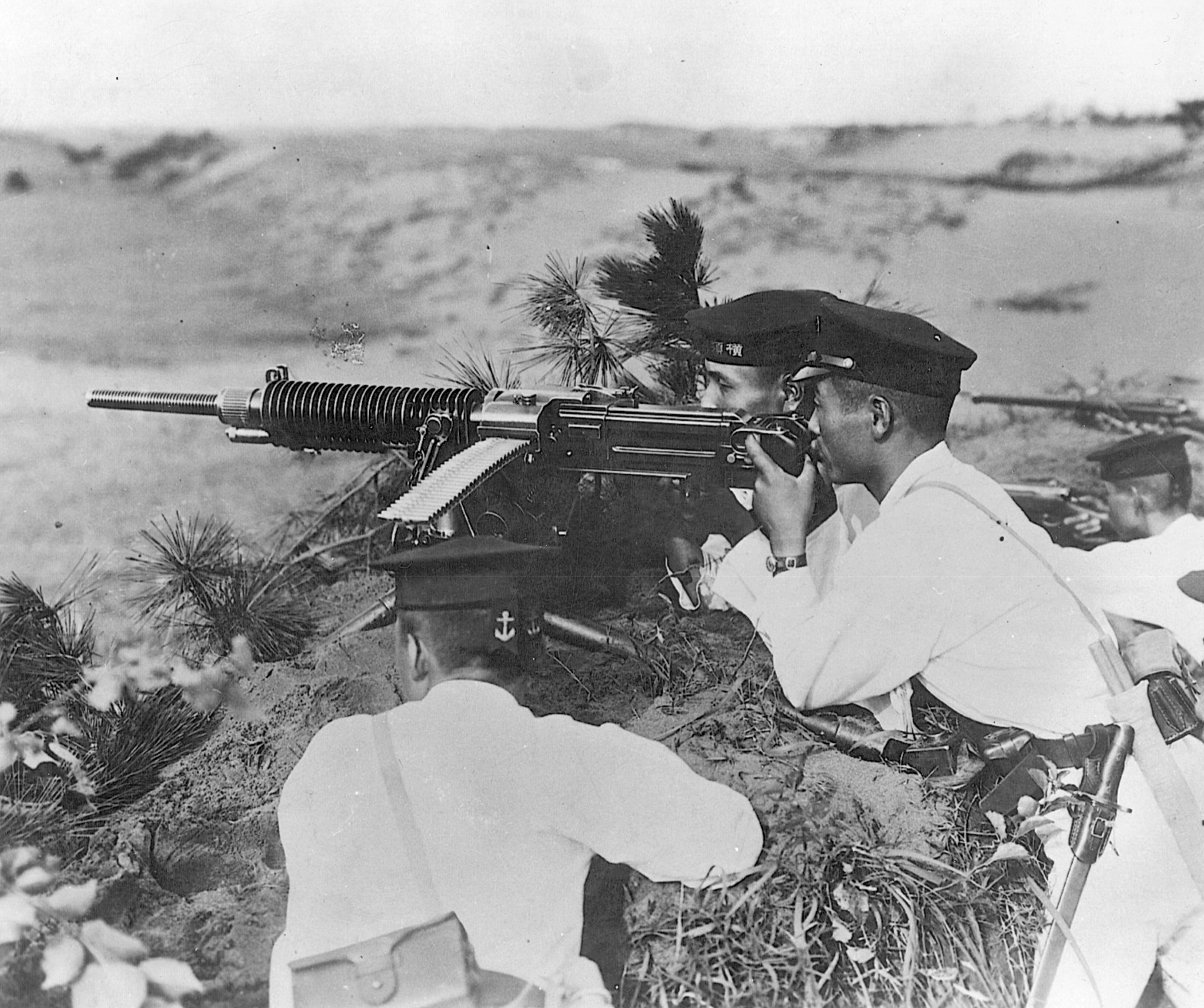 Clad in white uniforms and dress caps, Japanese soldiers fire a Nambu machine gun. Possibly a memento from his training days, this photo was found on the body of a dead Japanese soldier on Guadalcanal. 