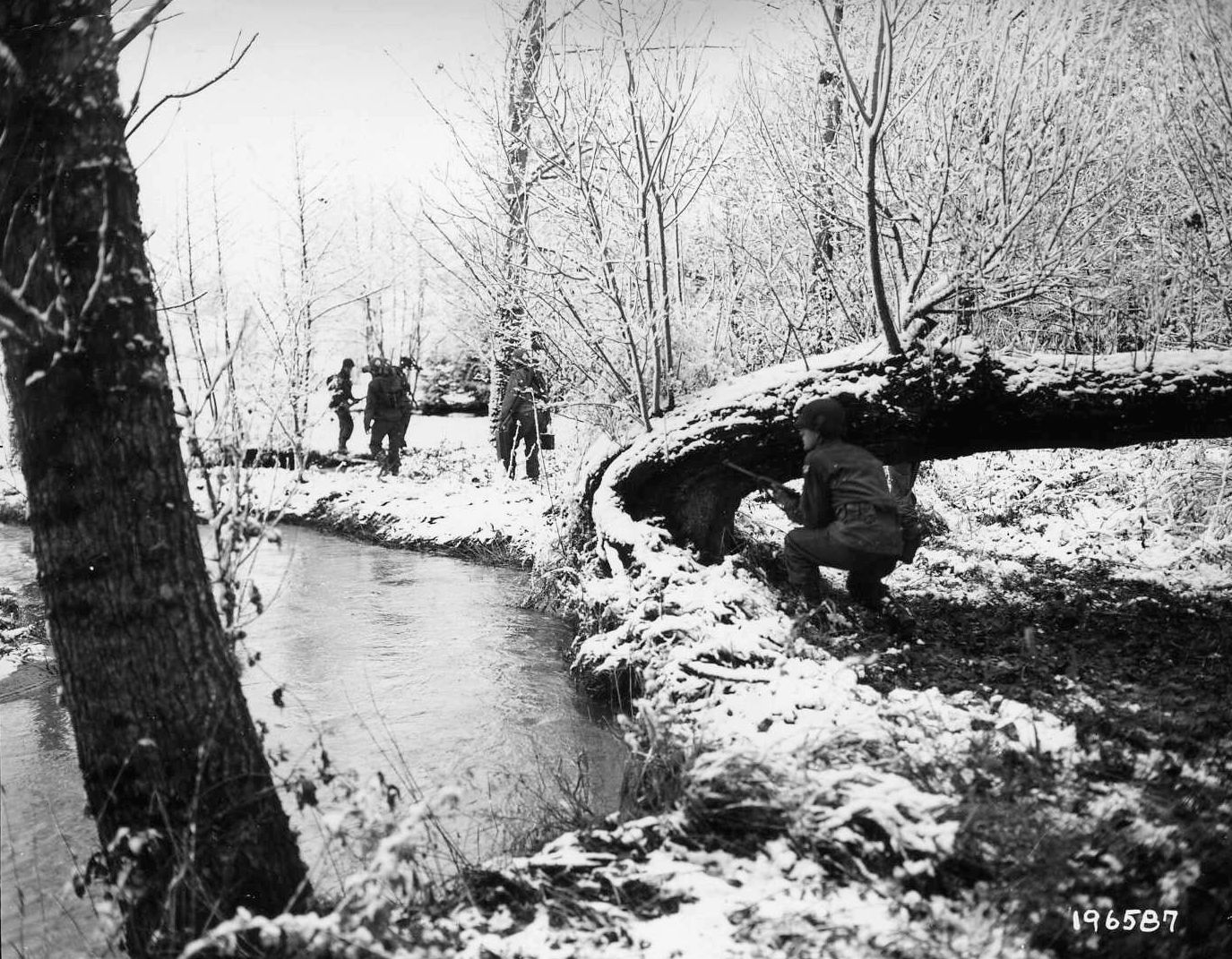 Near St. Helene, France, a heavy machine gun section of the 1st Battalion, 30th Regiment, 3rd Infantry Division moves forward along a stream under the watchful eye of a covering rifleman.