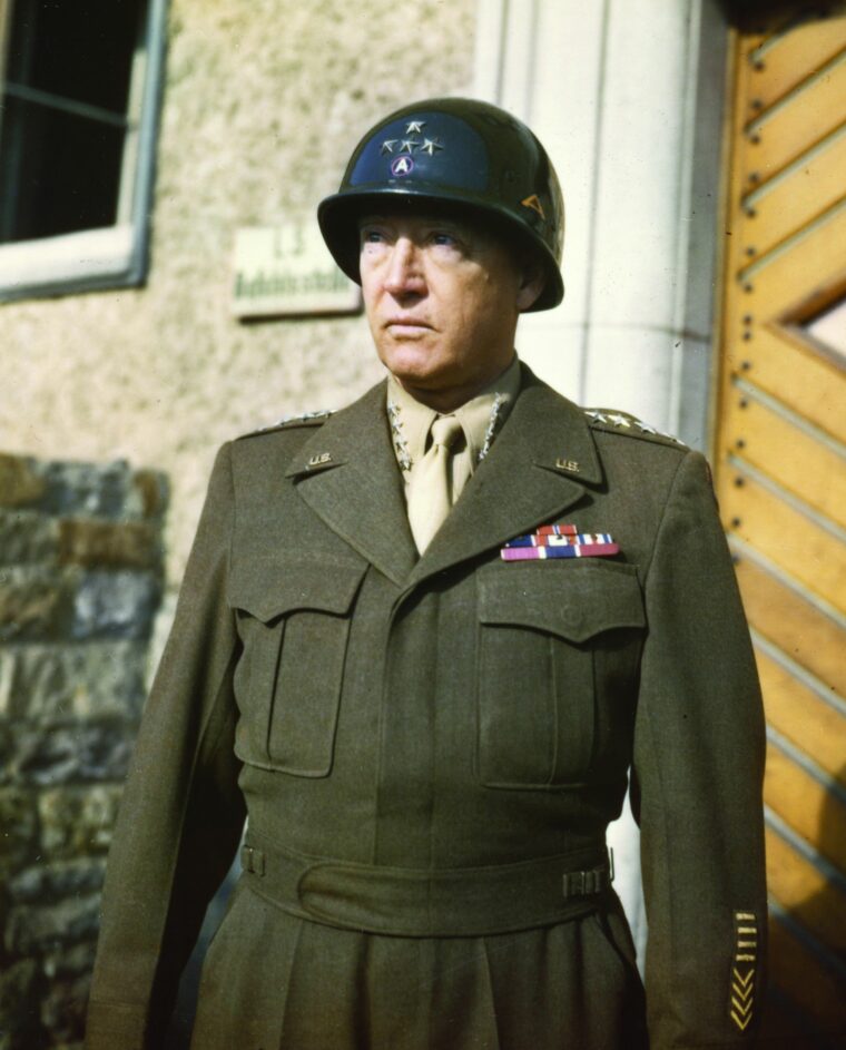 General George S. Patton, Jr., stands proudly in uniform. He wears the four stars of his rank along with the insignia of the Third and Seventh U.S. Armies on his helmet. (National Archives)