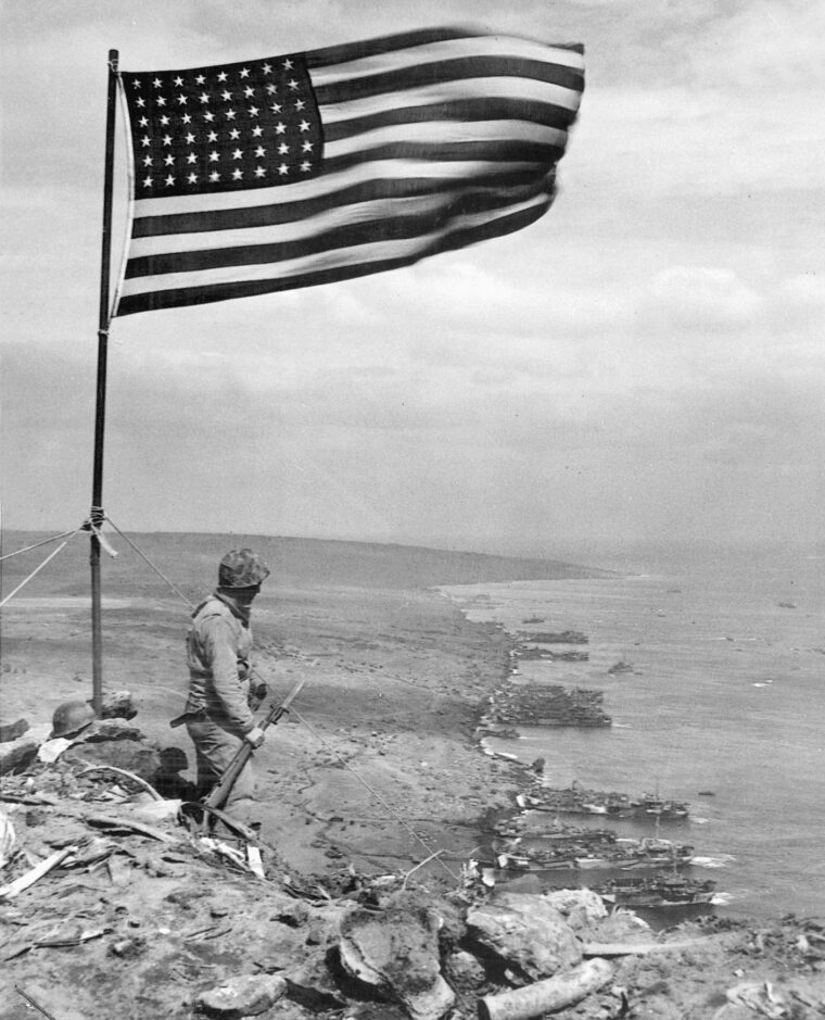 Waving in a stiff breeze, Old Glory is guarded by a lone sentinel on the summit of Mount Suribachi.