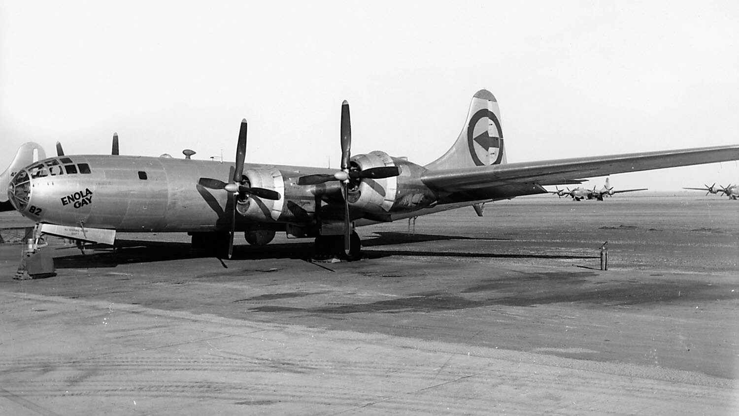 The four engine B-29 Superfortress Enola Gay sits on an airfield tarmac. The bomber’s tricycle landing gear is plainly visible in this photo. The B-29 featured numerous innovations, including a pressurized cabin. 