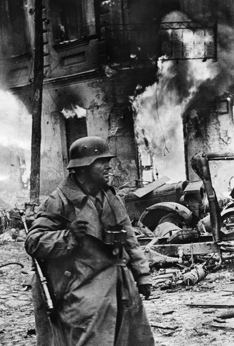 The strain of combat evident on his face, a German panzergrenadier in Zhytomyr, Ukraine, appears oblivious to the destruction around him. This photo was taken on December 21, 1943.