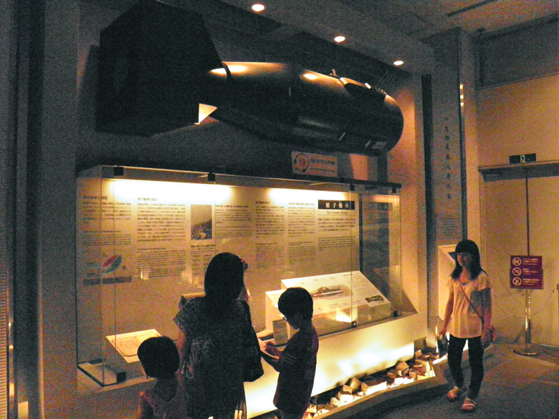 A full-size replica of the “Little Boy” atomic bomb is suspended above a display case in the Hiroshima Peace Memorial Museum. 