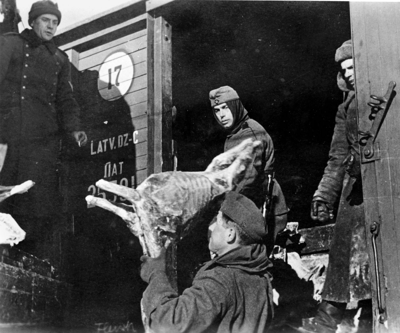 LATVIAN IMPORTS: German soldiers appear to be unloading provisions from a Latvian railroad car; Soviet Cyrillic lettering is visible.  Operation Barbarossa, launched on June 22, 1941, quickly overran the Baltic States of Latvia, Lithuania, and Estonia, displacing Red Army forces that had previously annexed and occupied those countries as a result of the 1939 German-Soviet Non-Aggression Pact that had enabled the division of Poland between the two countries.
