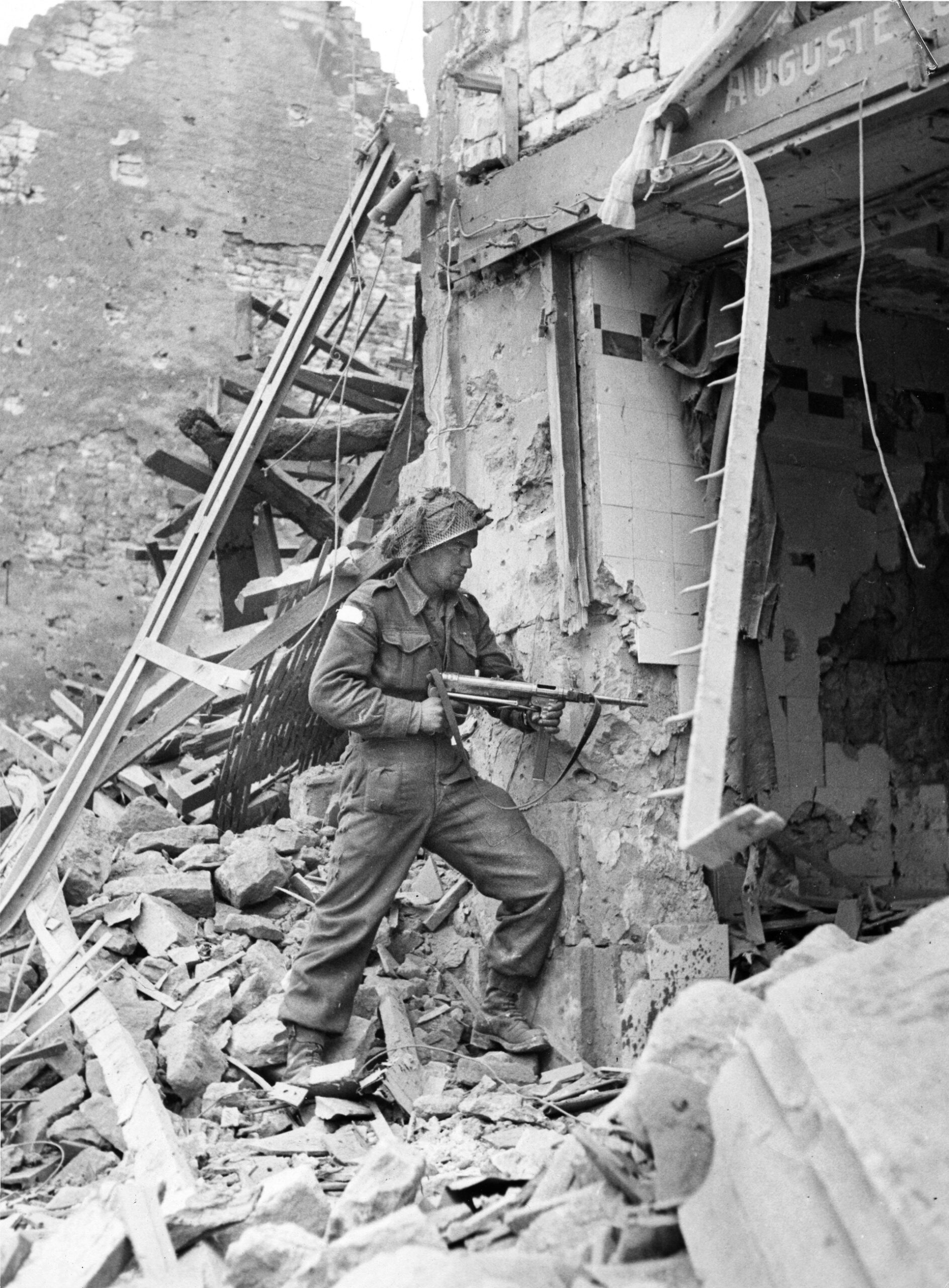 A soldier of the 3rd Canadian Infantry Division, armed with a German MP 40 submachine gun that he likely found on the battlefield, checks for signs of life in a demolished building in Normandy. The Canadians landed 14,000 men at Juno Beach on June 6, 1944, while another 1,000 came in by parachute and glider.
