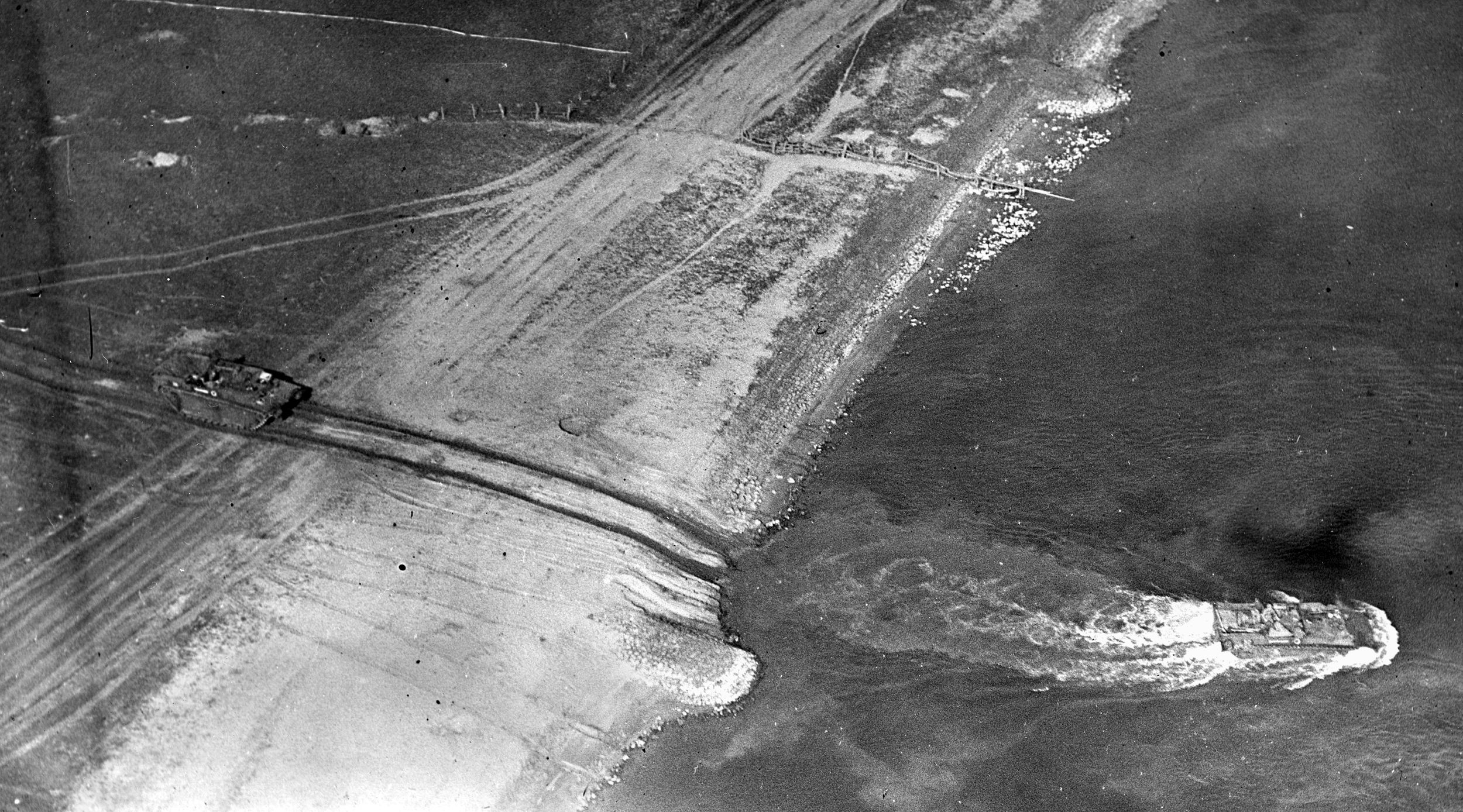 A British amphibious armored vehicle leaves the west bank of the Rhine, headed eastward. Another tank can be seen behind it on the bank. The photo was taken from a low-flying RAF plane on March 24, 1945.