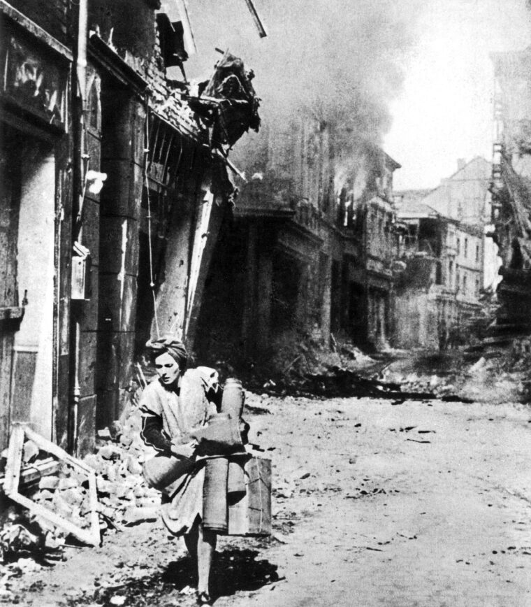 A woman runs through the streets with her last few possessions, perhaps heading to one of the city’s bunkers, during an American daylight air raid on Hamburg, July 1943.