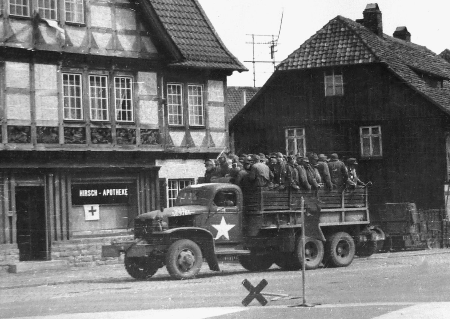 German prisoners of war riding in a 2.5-ton 6x6 truck are being transported to a POW stockade. Photo taken in Wolfenbuüttel, Germany, April 17, 1945.