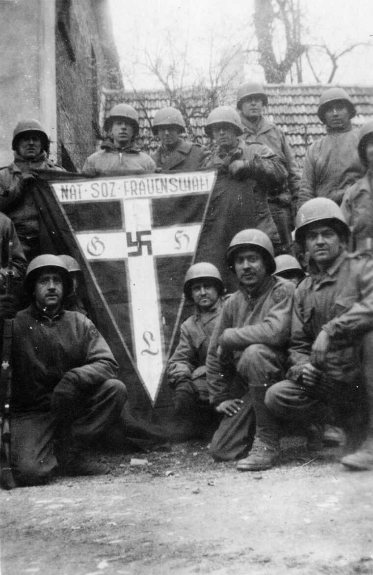 Members of the reconnaissance company (attached to battalion headquarters) pose with a souvenir banner of the National Socialist Women’s League, an organization that collected scrap metal, provided refreshments to German troops at railroad stations, and disseminated Nazi propaganda materials to women. 