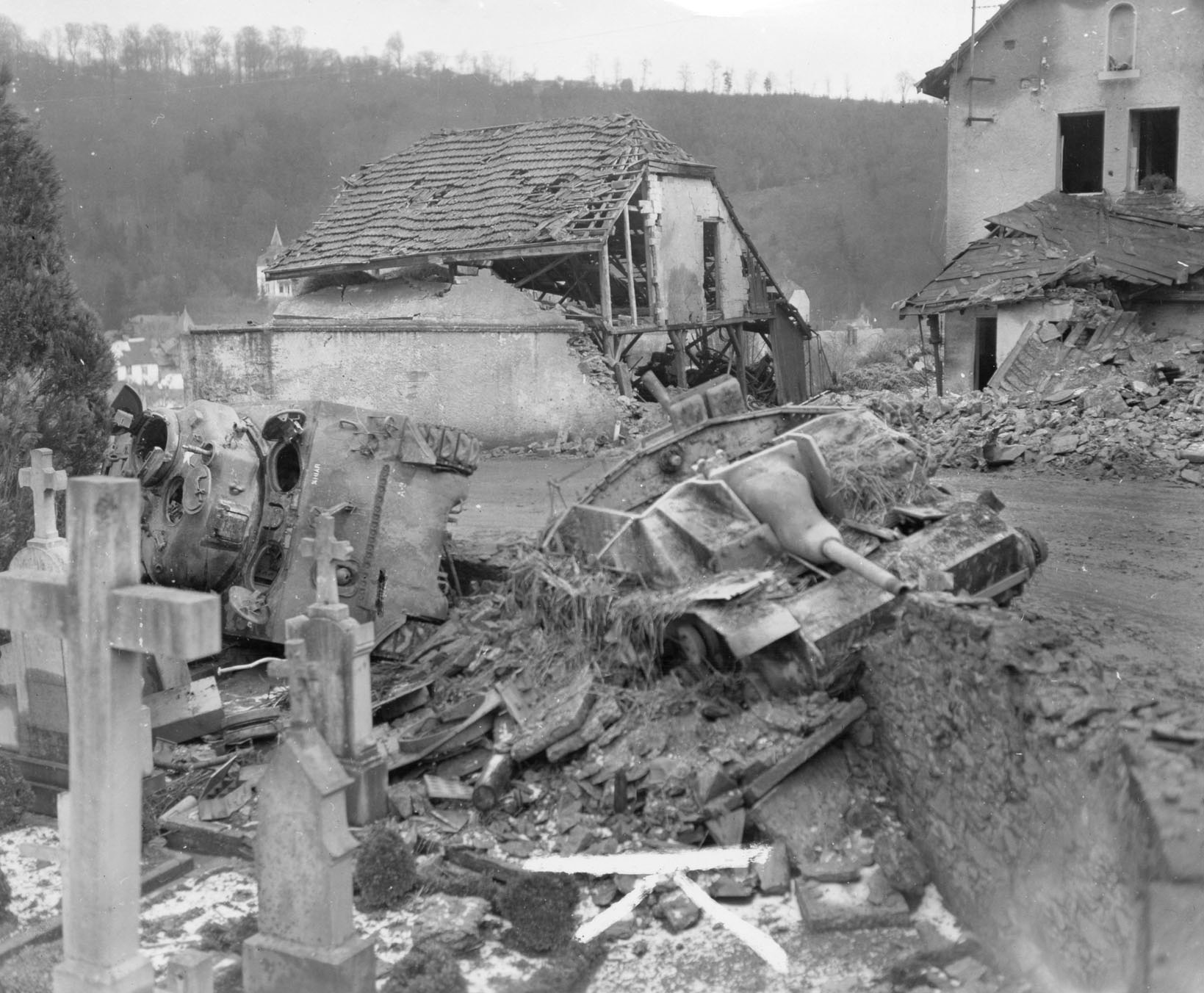 A Sherman tank from the 707th Tank Battalion lying on its side behind a knocked-out German Sturmgeschütz III at the cemetery outside Clervaux are mute testimony to the heavy fighting throughout Luxembourg.