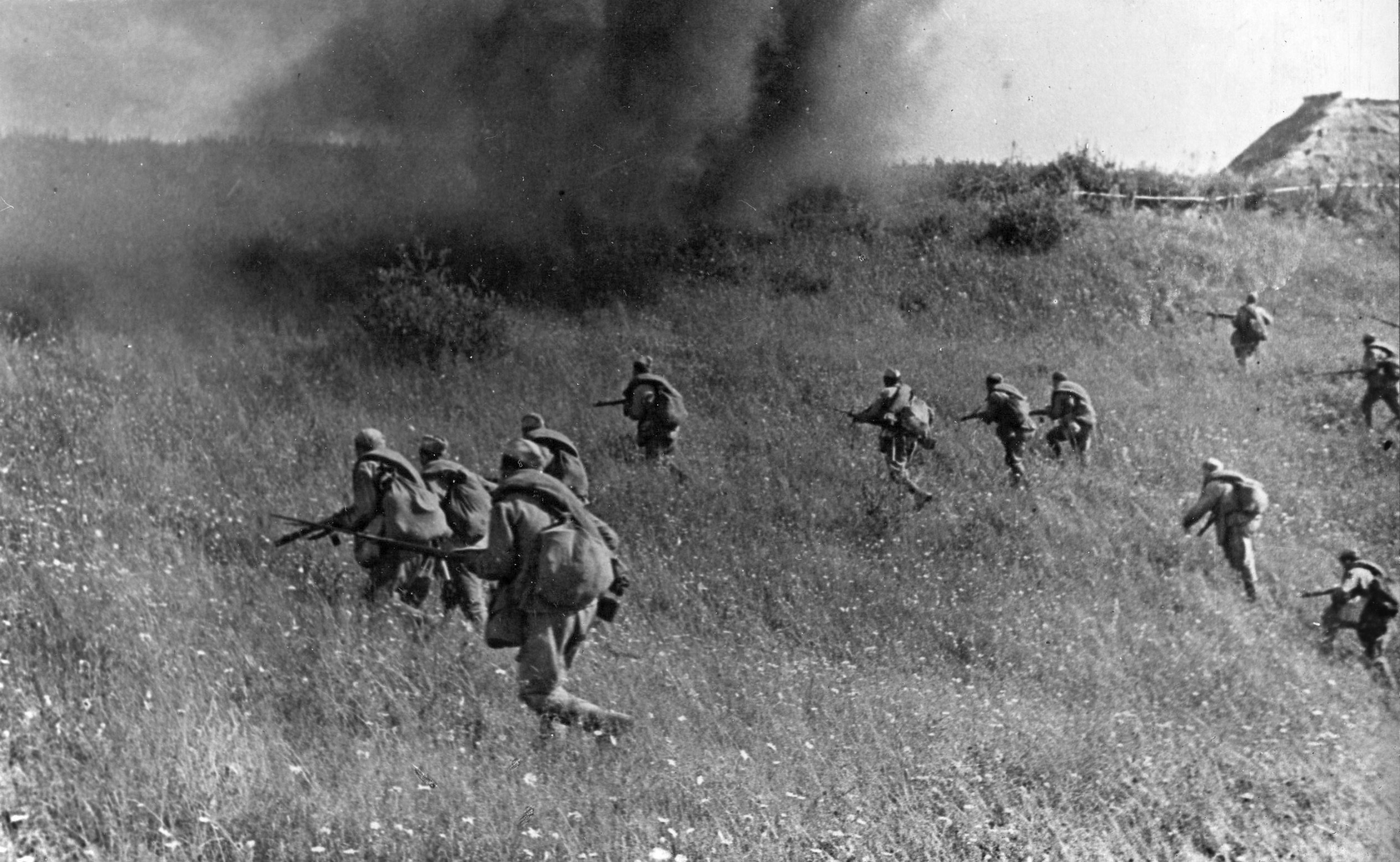 Red Army infantrymen advance as a shell explodes in front of them and throws up a curtain of smoke and debris. Out of the frame, Soviet tanks have taken the lead in this assault somewhere in the Ukraine.