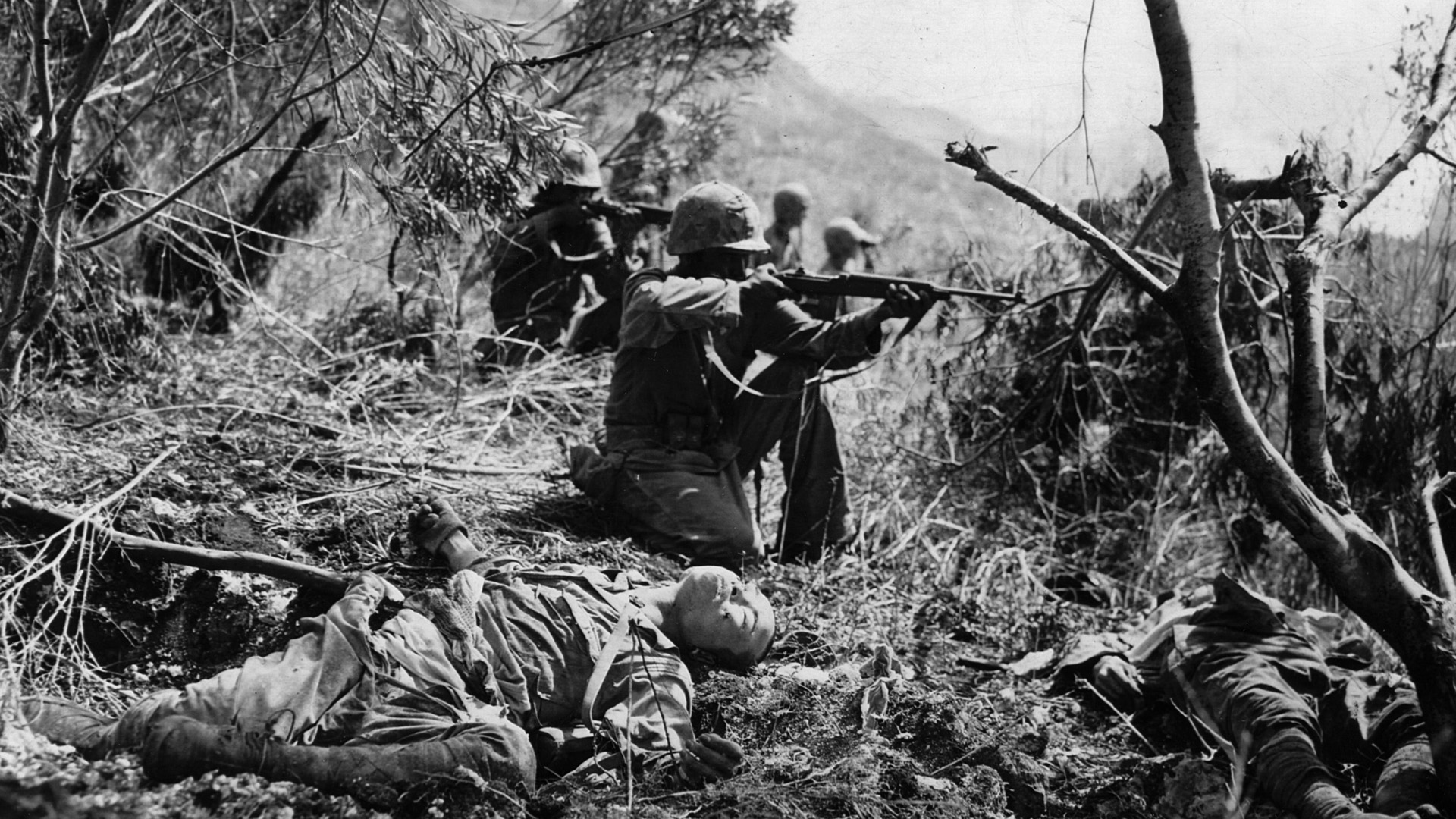 Amid the bodies of dead Japanese soldiers, a Marine of the U.S. 2nd Division raises his M1 carbine to take aim at the retiring enemy on Saipan during the advance on Mount Marpi. The bitter battle for Saipan resulted in heavy casualties for both sides.