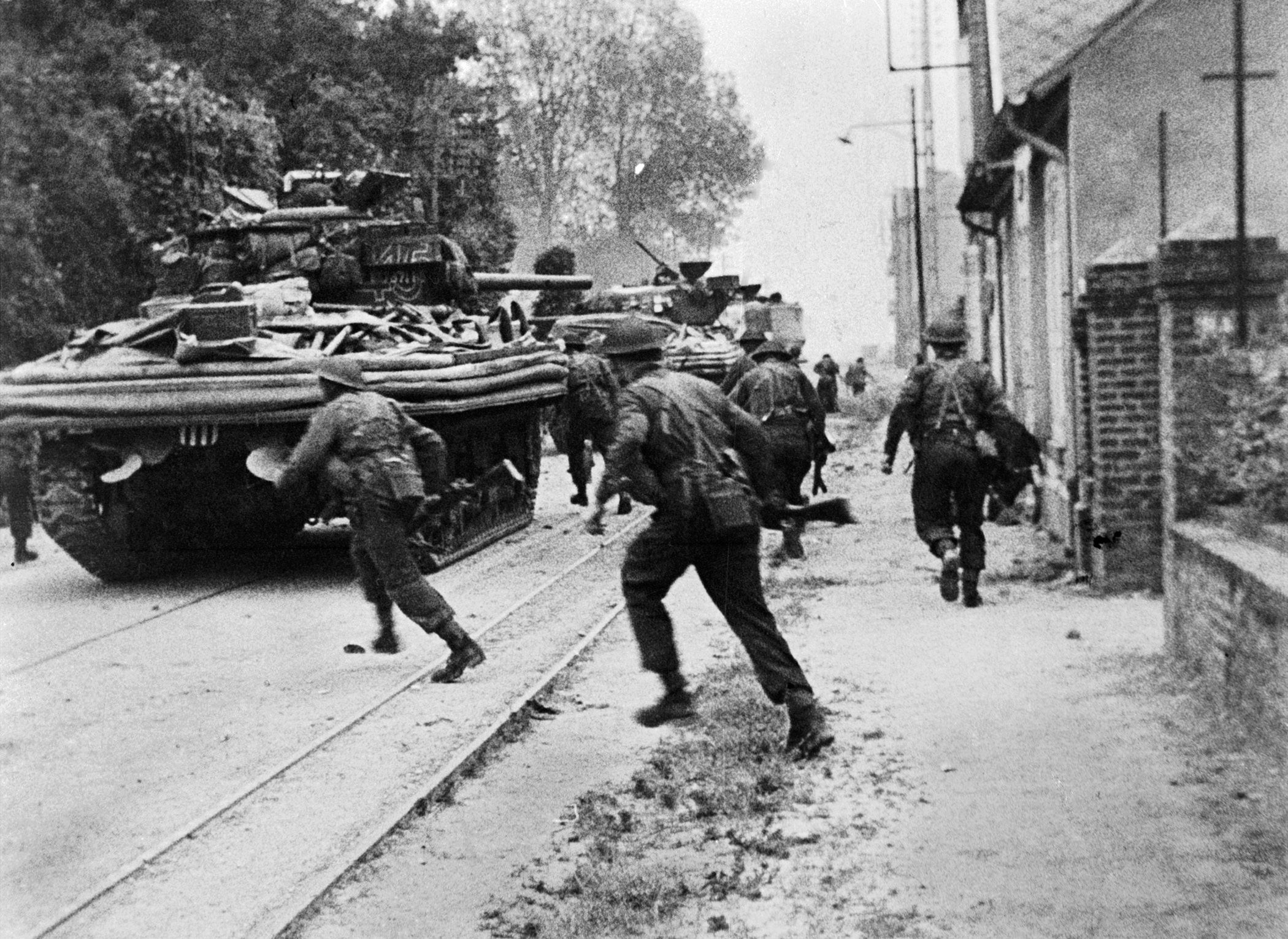 No. 4 Commando engages in house-to-house fighting with the Germans at Riva Bella, near Ouistreham. Sherman DD tanks of B Squadron, 13/18th Royal Hussars are providing fire support and cover.