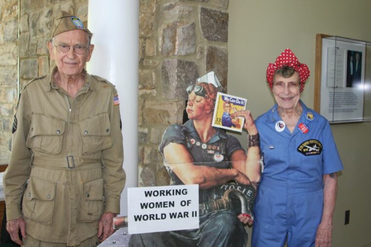 American Rosie the Riveter Association founder Dr. Frances Tunnell Carter and her husband, John Carter, a former paratrooper, pose with a Rosie the Riveter poster.