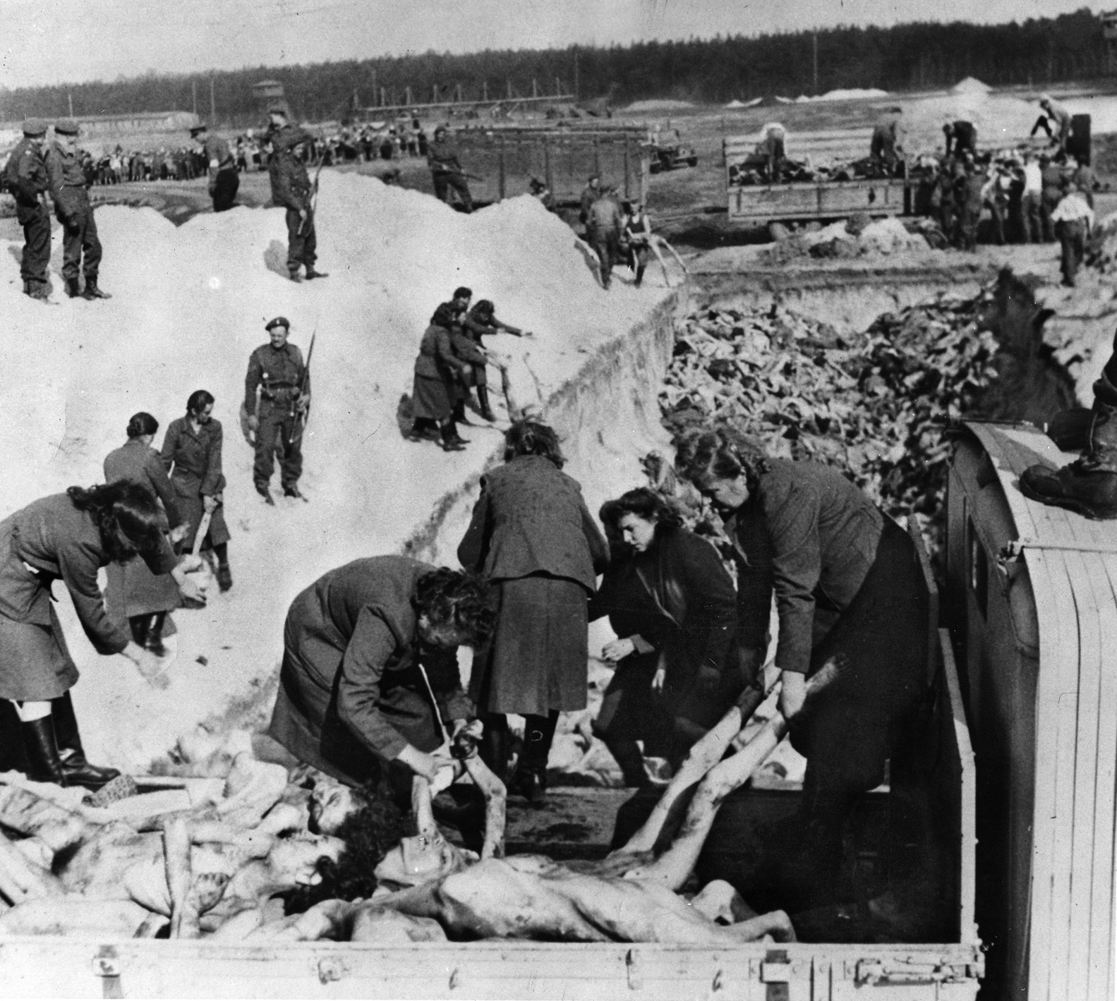 Women’s work: British soldiers look on as Aufseherinnen at Bergen-Belsen are forced to dispose of 10,000 corpses in a mass grave.