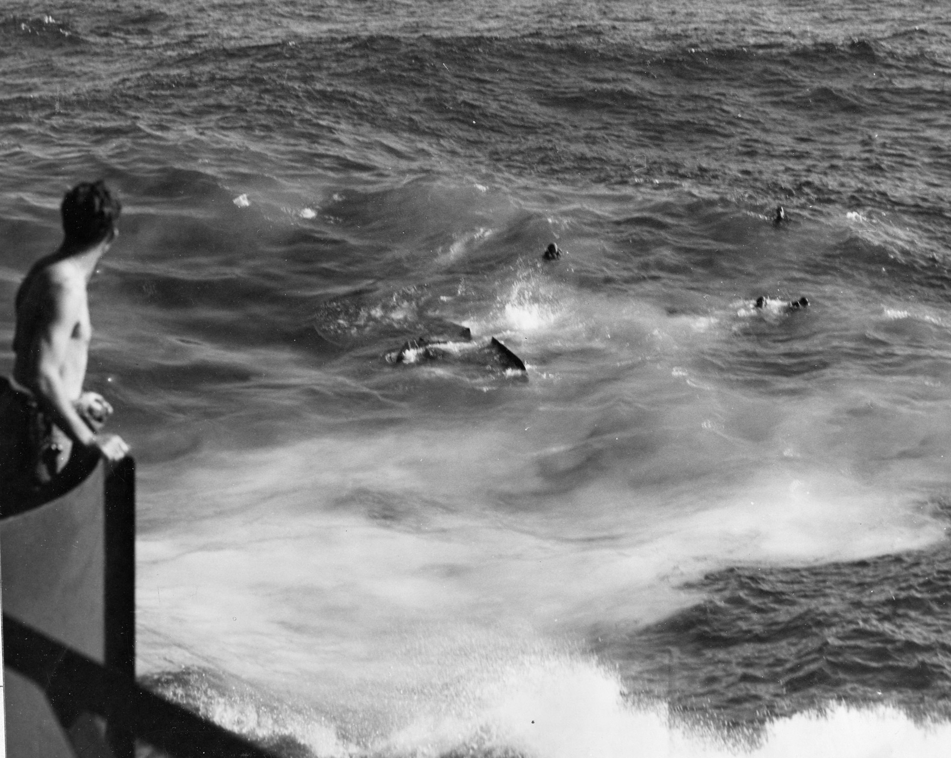 Under the watchful eye of a sailor from the USS Morris, the crew await pick up as the bomber sinks, tail last.