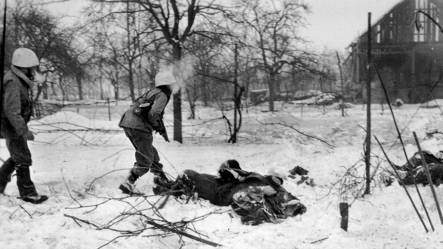 U.S. troops advance cautiously past the bodies of several dead German soldiers during combat on the outskirts of Jebsheim.