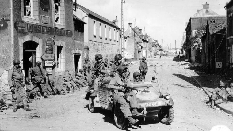 Paratroopers from the 101st Airborne Division commandeer a German Kubelwagon in Carentan. Sergeant Don Malarkey witnessed the regimental chaplain giving last rites to the wounded in Carentan as enemy fire fell.