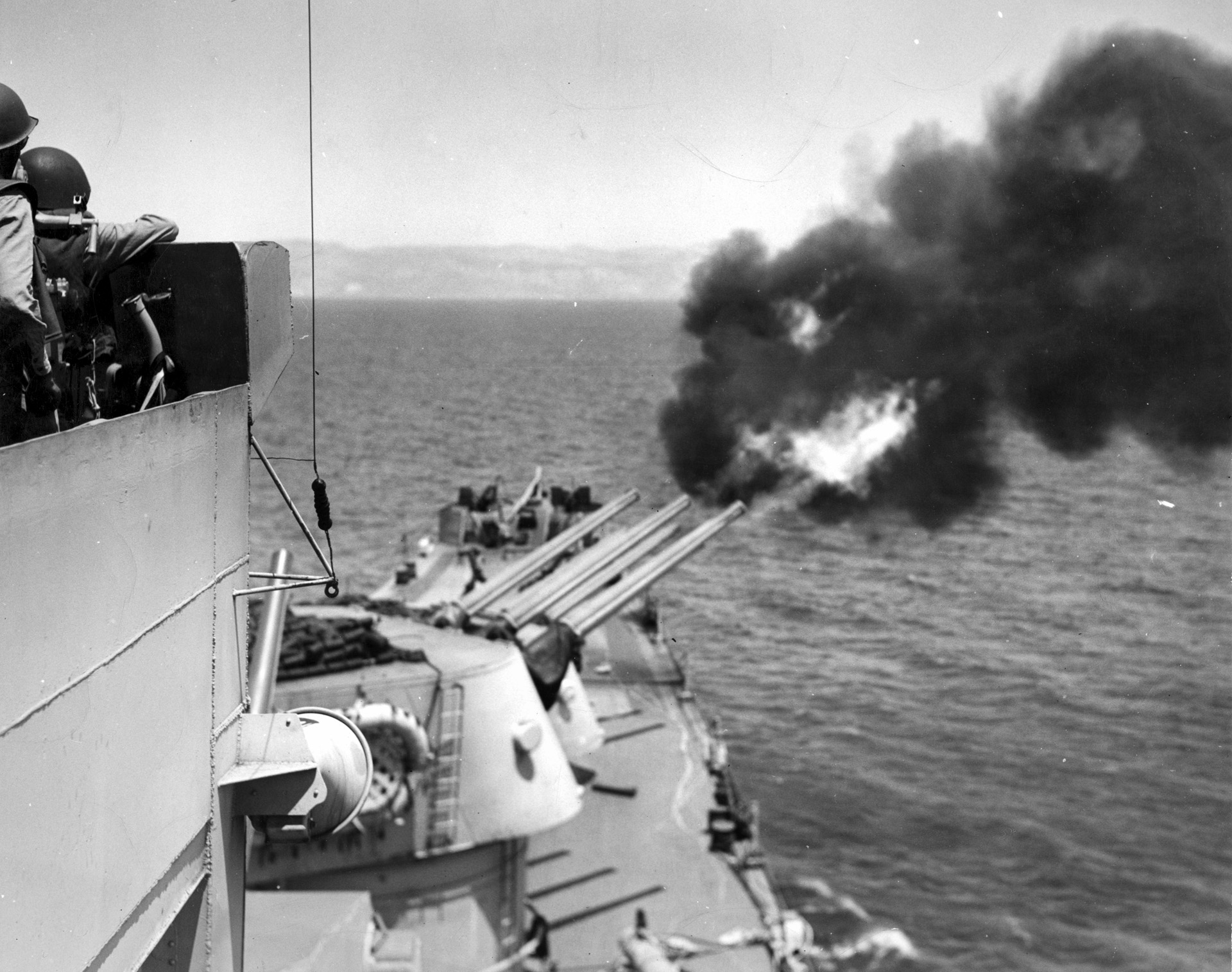 In support of operations on land, the light cruiser USS Birmingham fires a salvo from its 6-inch guns off the coast of Agrigento, Sicily, during Operation Husky.