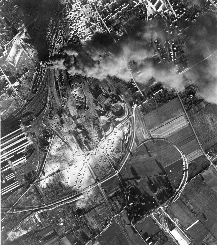 A high-angle BDA (bomb-­damage assessment) photo of Nevers, July 17, 1944. Bomb craters and smoke from burning freight cars in the railroad marshalling yard are clearly visible. (photo by U.S. Army Air Forces)