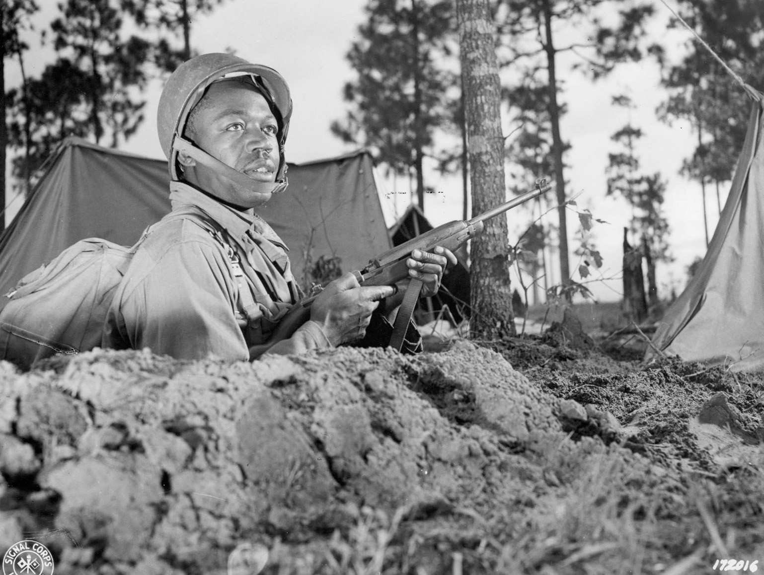 Now outfitted with the modern M-1 helmet and an M-1 carbine, Private Clarence Jones, 594th Field Artillery Battalion, is photographed during the Third Army Louisiana Maneuvers, April 1943.